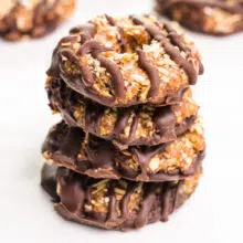 A stack of no-bake Samoas cookies sits in front of more cookies in the background.