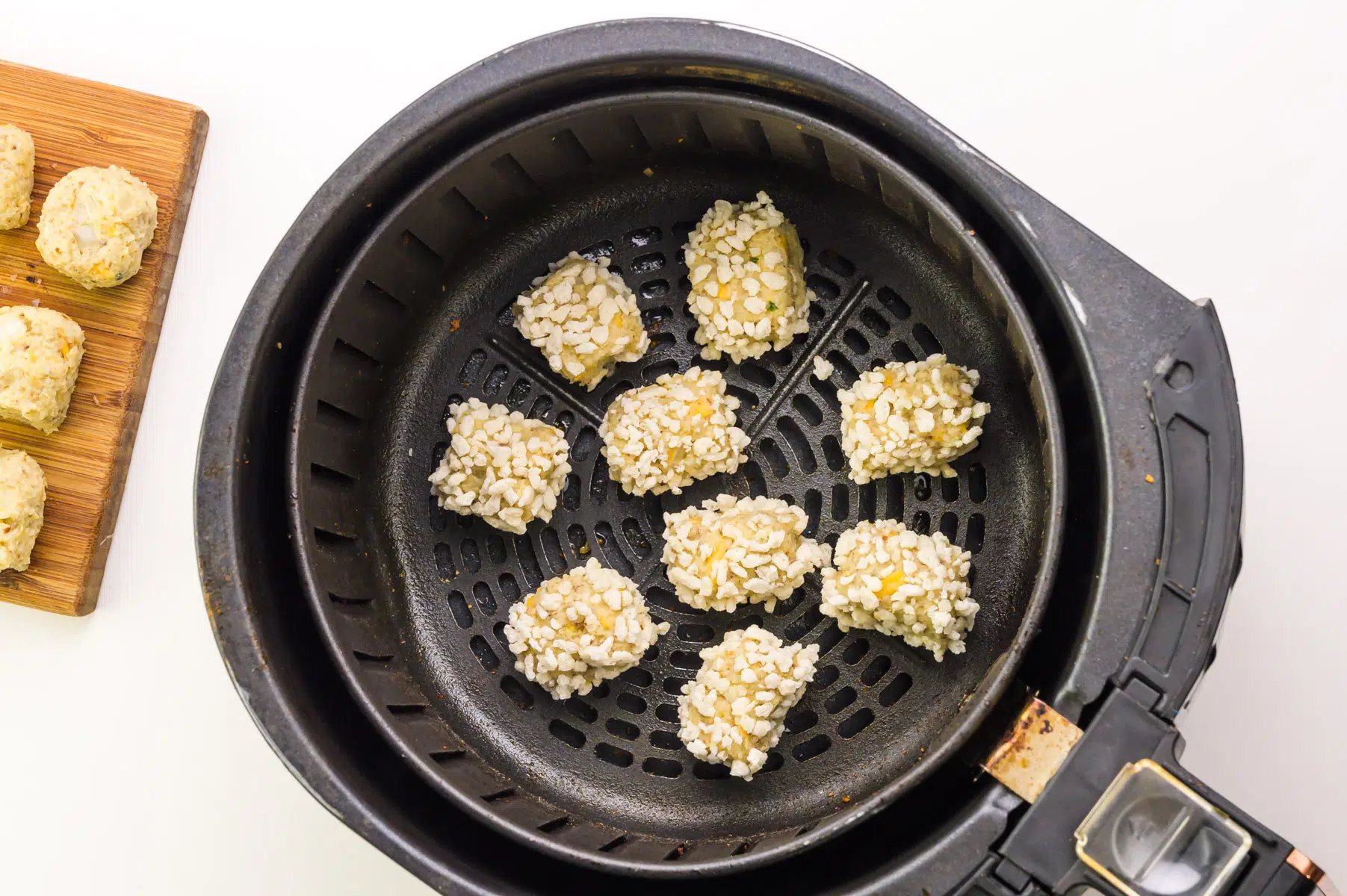 Cauliflower tots are in the bottom of an air fryer basket.