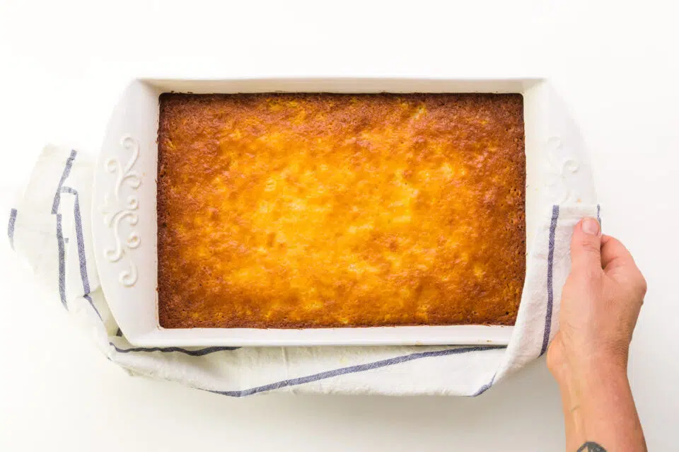 Looking down on a freshly-baked cake in a pan. The top is golden brown.