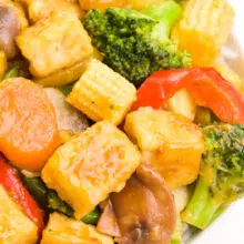 A bowl of teriyaki tofu stir fry features veggies and fried tofu with a thick sauce.