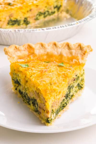 A slice of Just Egg quiche sits on a plate in front of the pan with more quiche.
