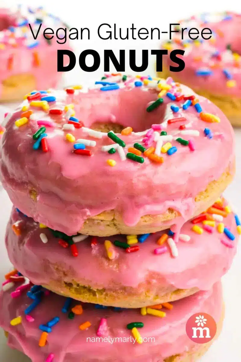 Donuts with pink glaze are stacked with more donuts behind the stack. The text at top reads, Vegan Gluten Free Donuts.