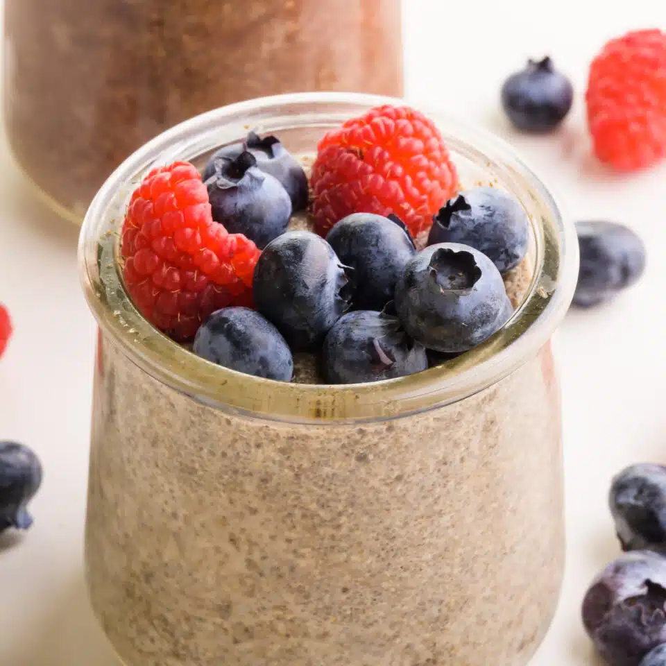 A closeup of chia pudding in a jar with fresh fruit on top.