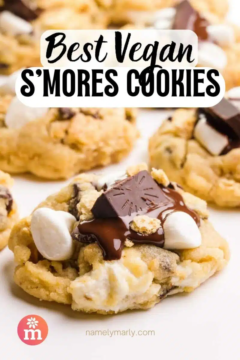 A cookie with melted chocolate and marshmallows sits in front of other cookies. The text reads, Best Vegan S'Mores Cookies.