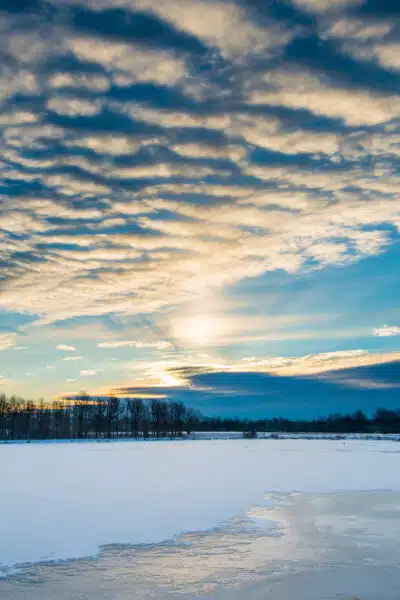 A photo of a winter landscape showing a frozen lake with clouds overhead.