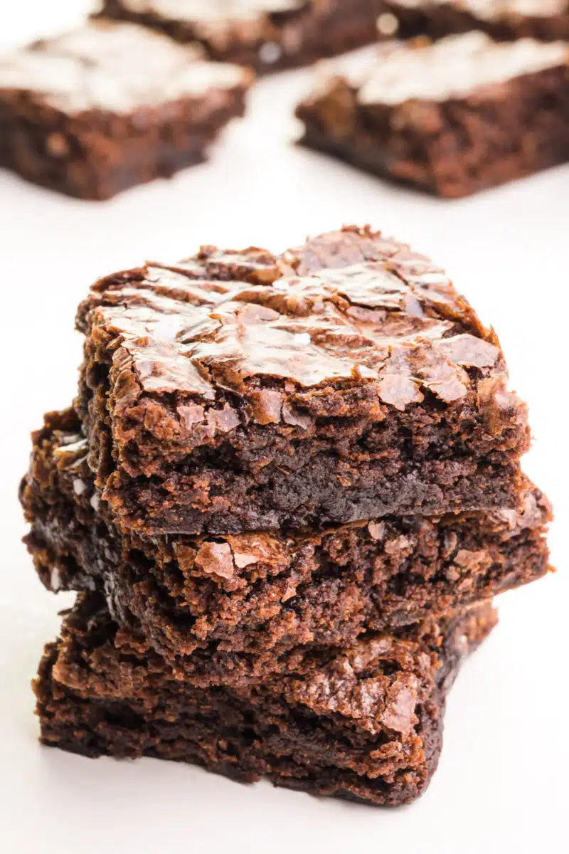 A stack of three slices of vegan brownies from a box sits in front of more brownies in the background.