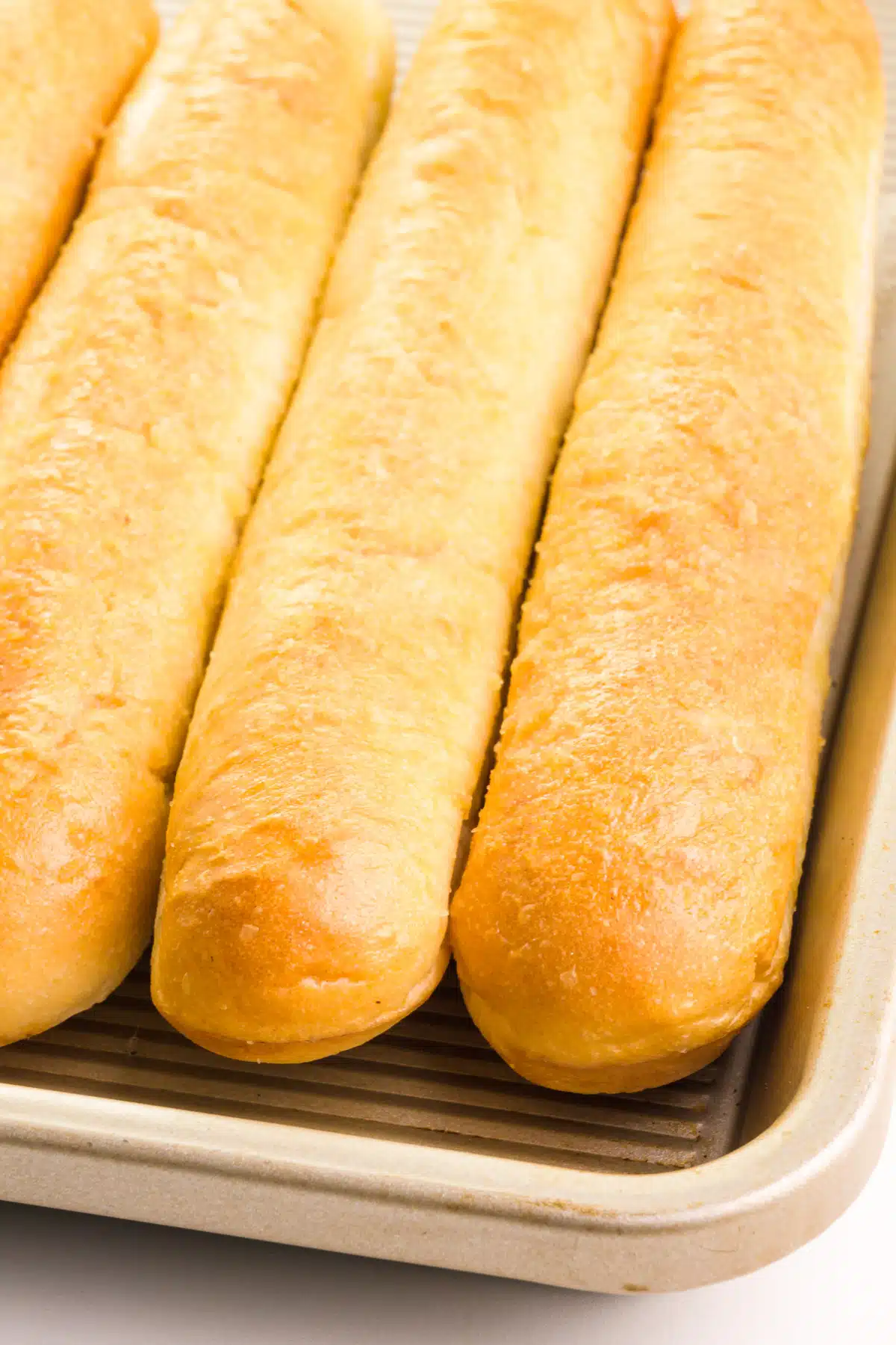 Breadsticks are lined up in a pan, ready to be reheated.