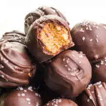 A closeup of cashew butter truffles on a plate. The top one has a bite taken out.