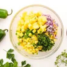 Looking down on a bowl with corn, chopped herbs, onions, mango, and more.