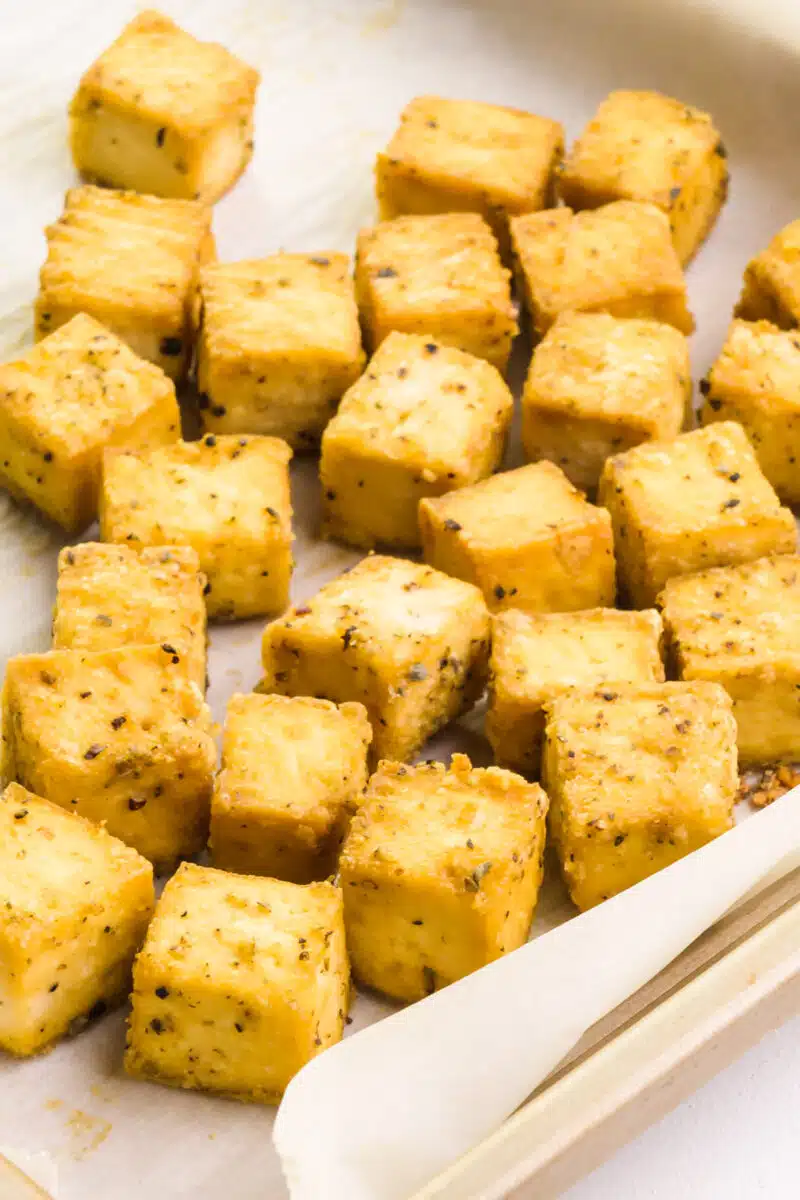 Freshly baked tofu sits in a baking pan lined with parchment paper.