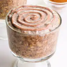Looking at a bowl of cinnamon roll overnight oats with cinnamon swirls on top.