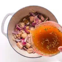Vegetable broth is being poured into a pot with other vegetables and jackfruit.