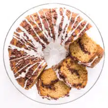 Looking down on a coffee cake on a plate with several slices cut out and sitting beside the cake.