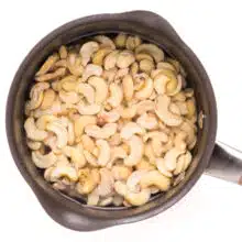 Looking down on a saucepan with cashews soaking in water.