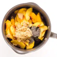 Peaches are topped with brown sugar and chia seeds in a saucepan.